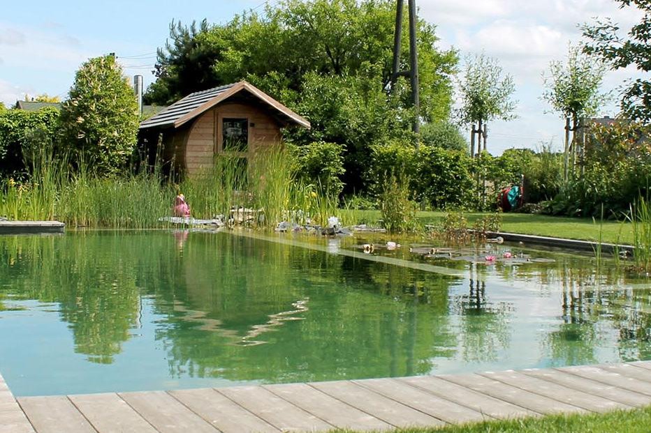Ein breiter Schwimmteich eingebettet in einen Regenerationsbereich und einer Holzterrasse mit Sauna in Hünxe