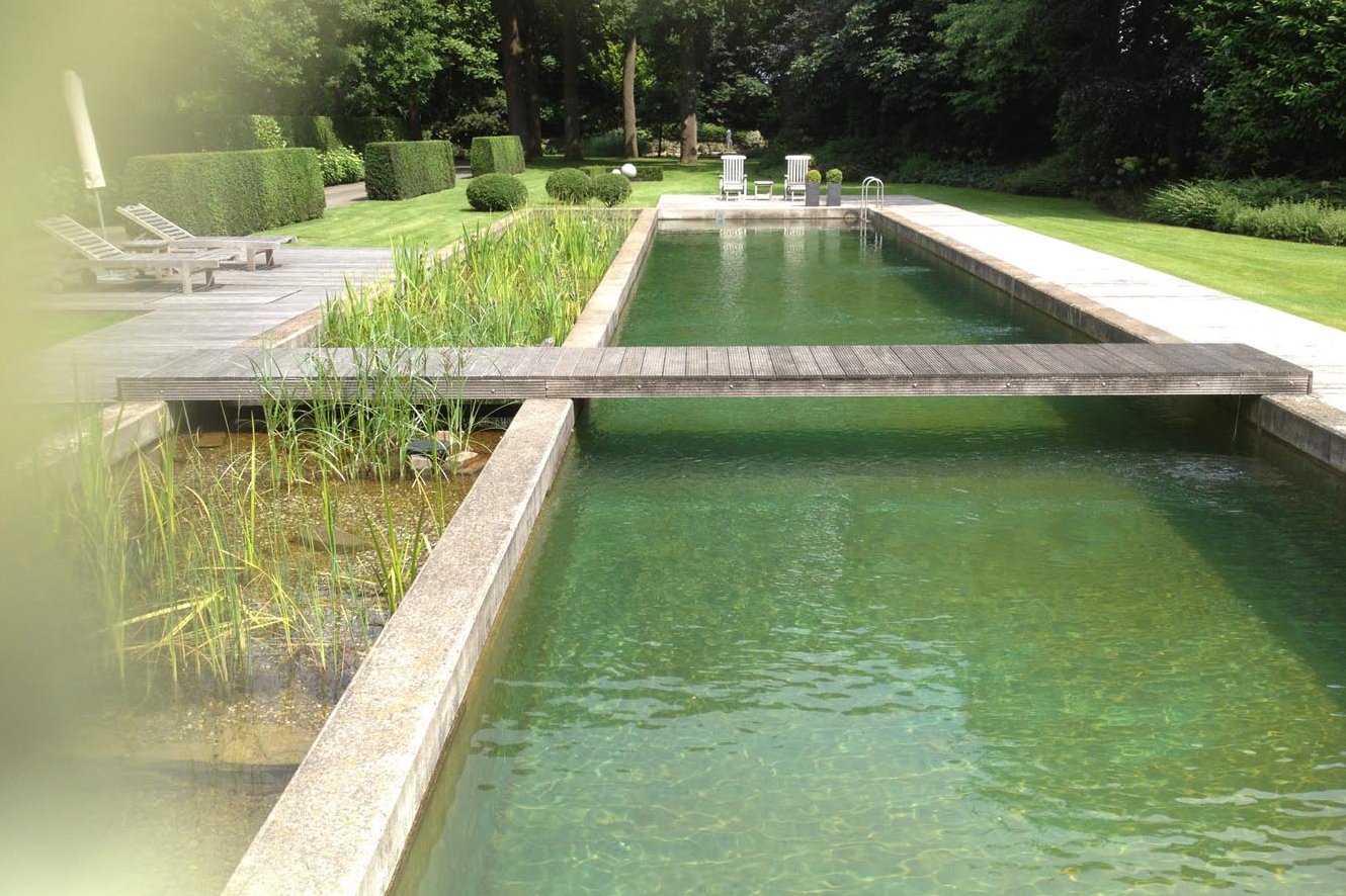 Ein großzügige Garten mit einem Schwimmteich aus Beton mit großem Schwimmbereich und gleichgroßer Regenerationszone. Ergänzt durch einen umlaufenden Holzsteg und diversen Holzterrassen. 