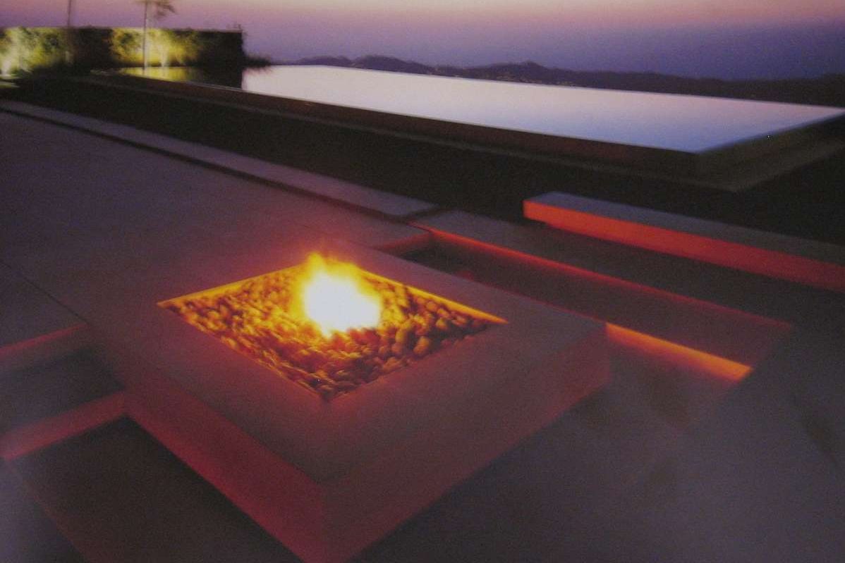 Eine Feuerstelle aus Stein mit Blick auf einen Erlebnis Schwimmteich in einem Garten in Wesel