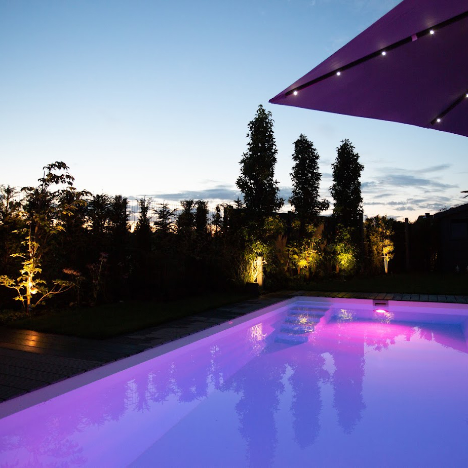 Ein Polyesterbecken von Garten Bitters mit lilaner Wasserbeleuchtung.