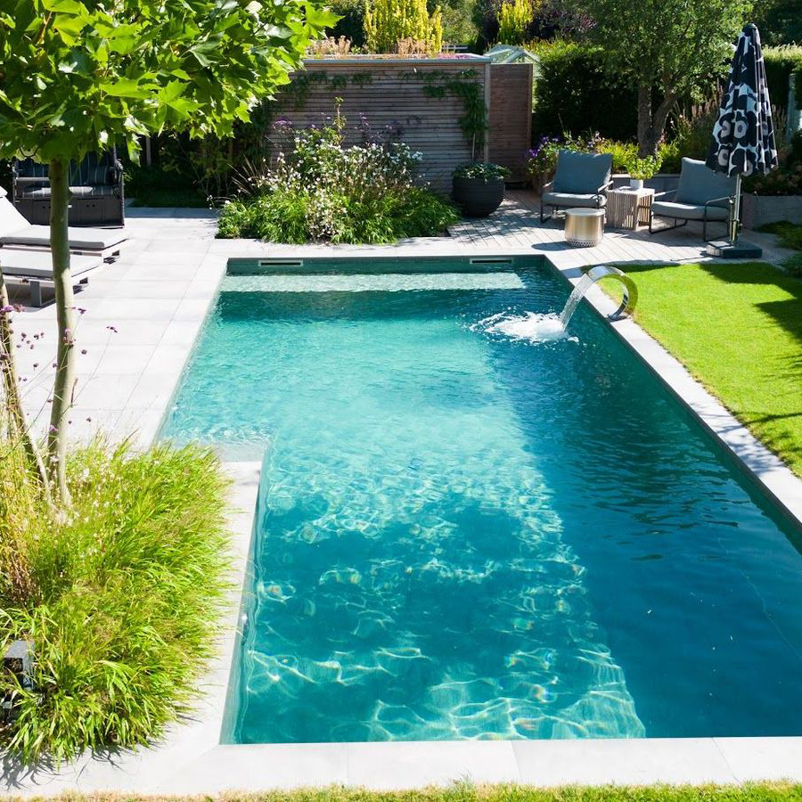 Ein Naturstein-Pool von Garten Bitters mit einer Schwallbrause und einem Sonnenschirm, Sitzgarnitur im Hintergrund