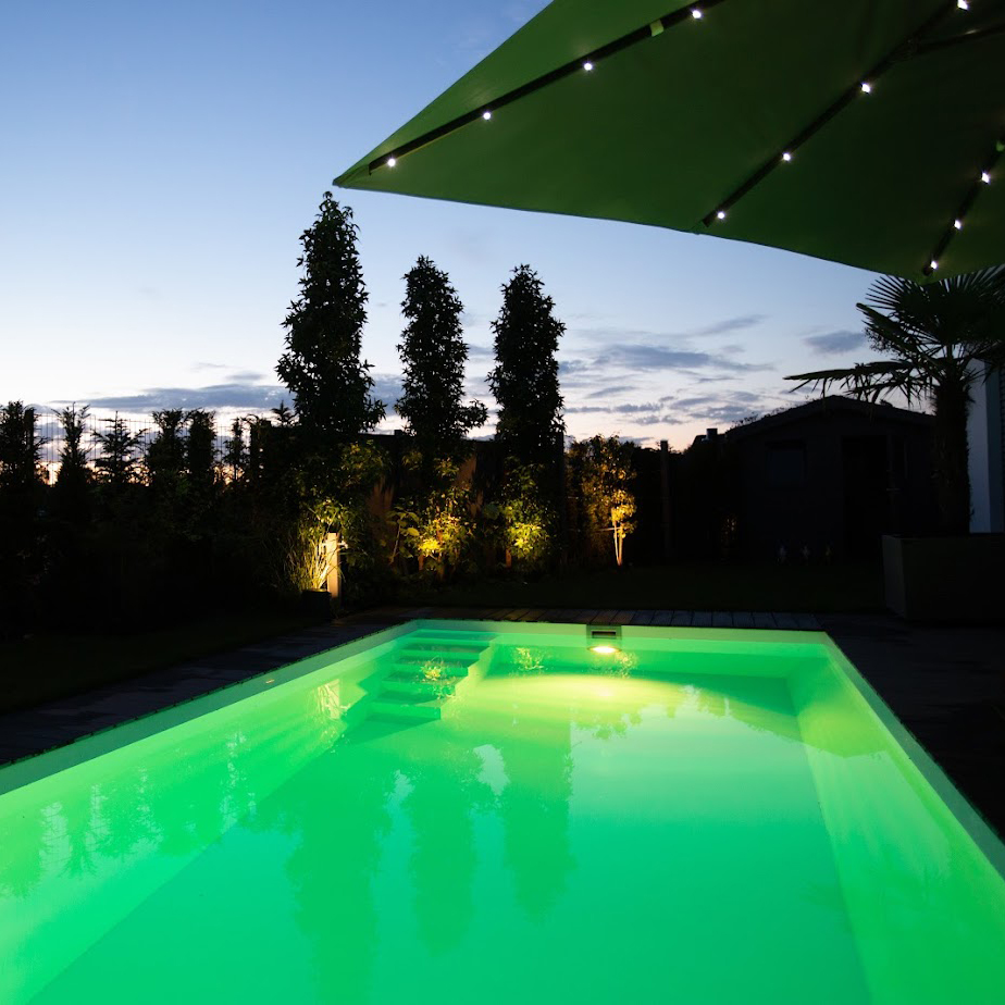 Ein Fertigbecken von Garten Bitters mit Treppe und grüner Beleuchtung.