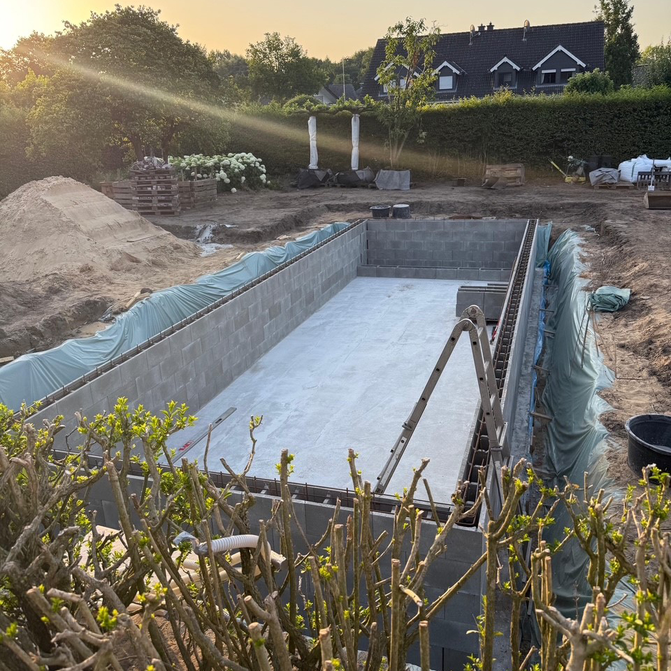 Eine Schwimmteich in der Bauphase bei Sonnenuntergang, begleitet von Garten Bitters.