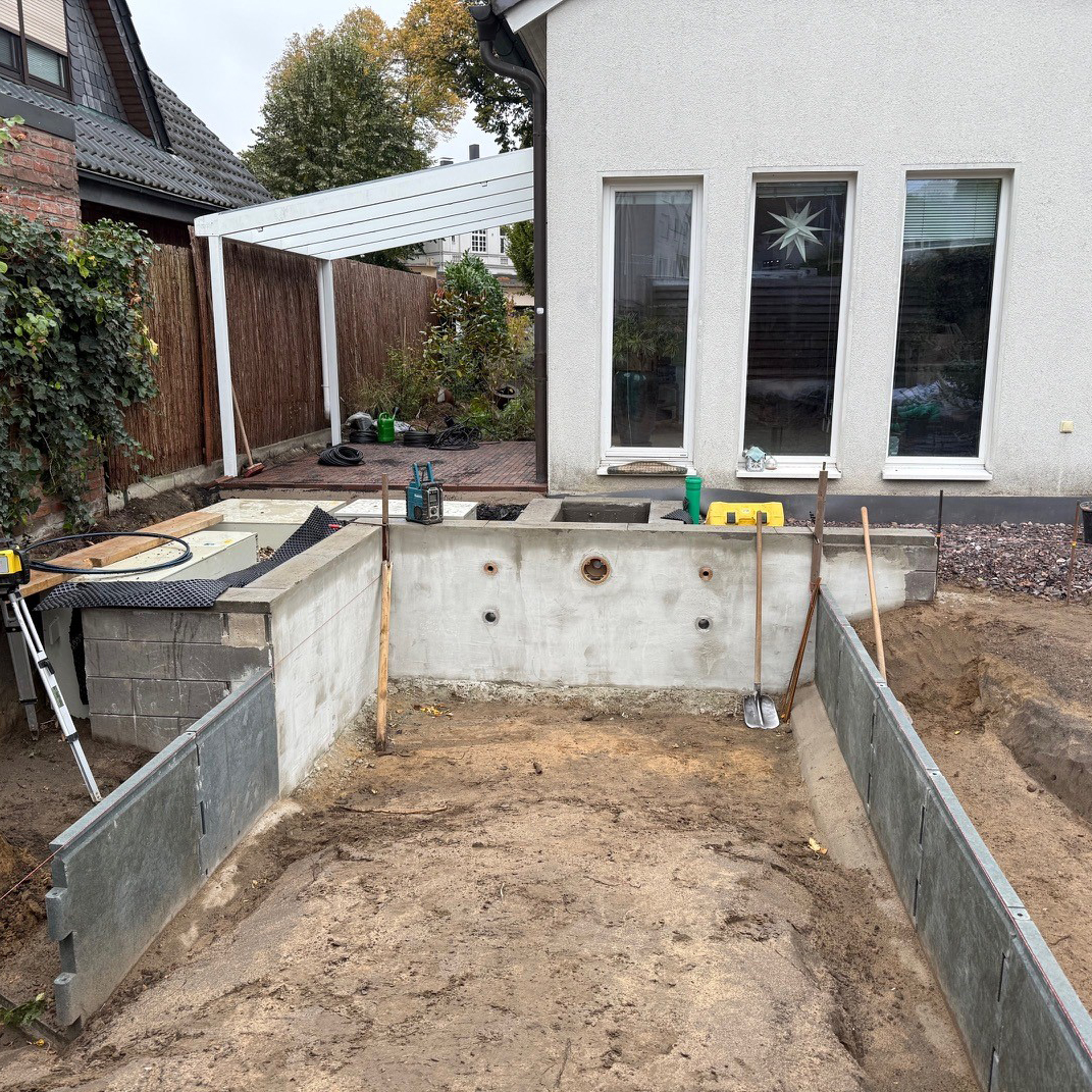 Ein Teichkörper in der Bauphase, vor einem wießen Haus.