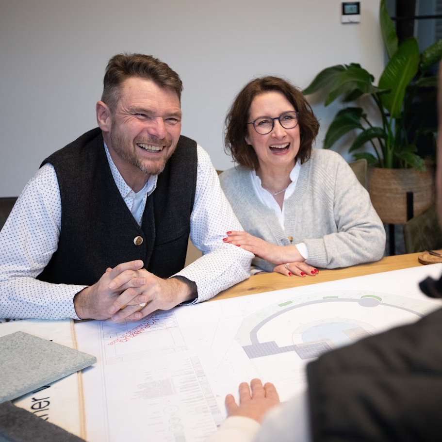 Zwei Kunden von Garten Bitters lassen sich zur Gartenplanung beraten und habe Pläne vor sich liegen.